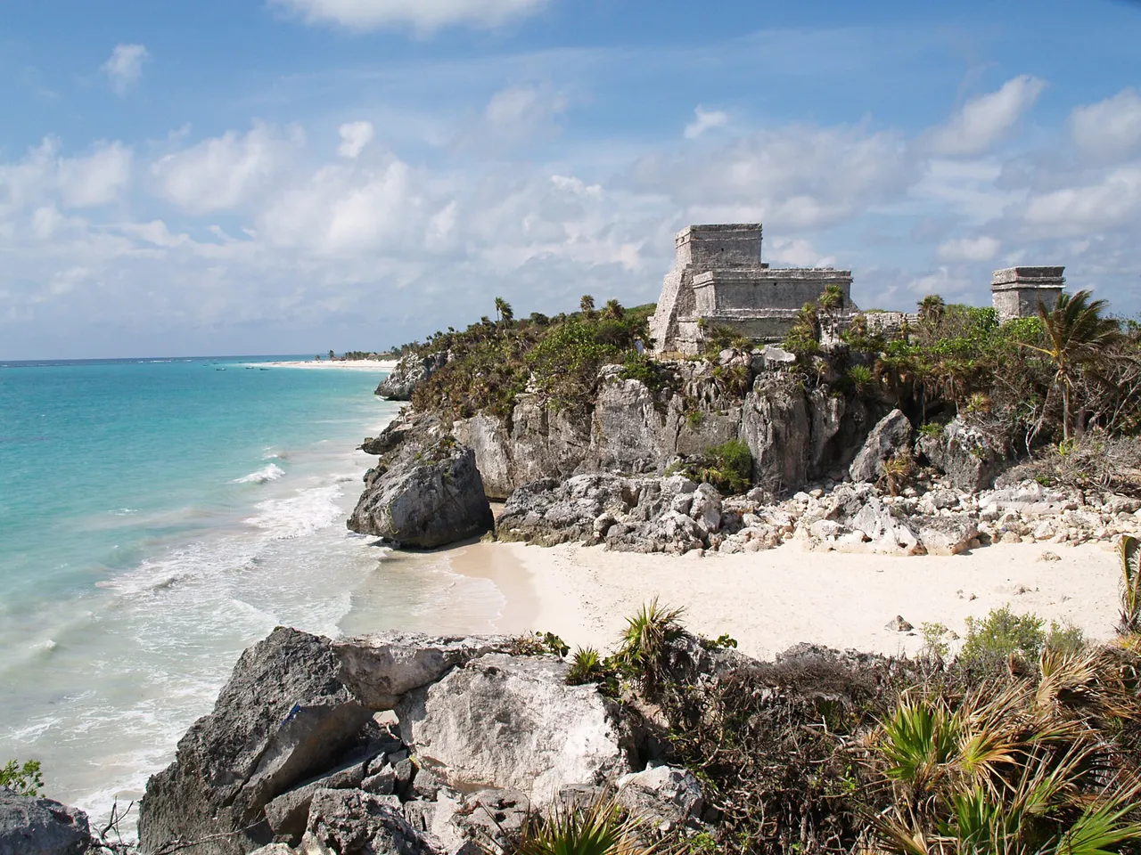 Tulum's El Castillo on the clifftop next to a white-sand beach and turquoise sea