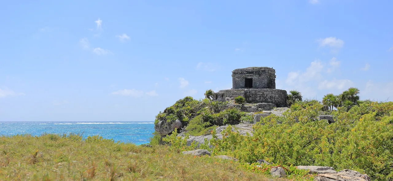 Panoramic view of Tulum's Temple of the God of the Wind on the rocks, with the Caribbean Sea behind